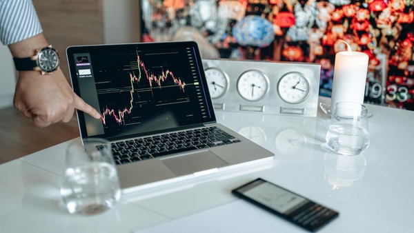 Laptop showing a trading chart next to clocks representing exchange processing time